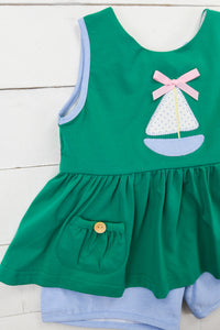 a green dress with a sailboat applique on it