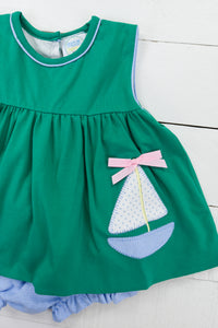 a green dress with a sailboat applique on it